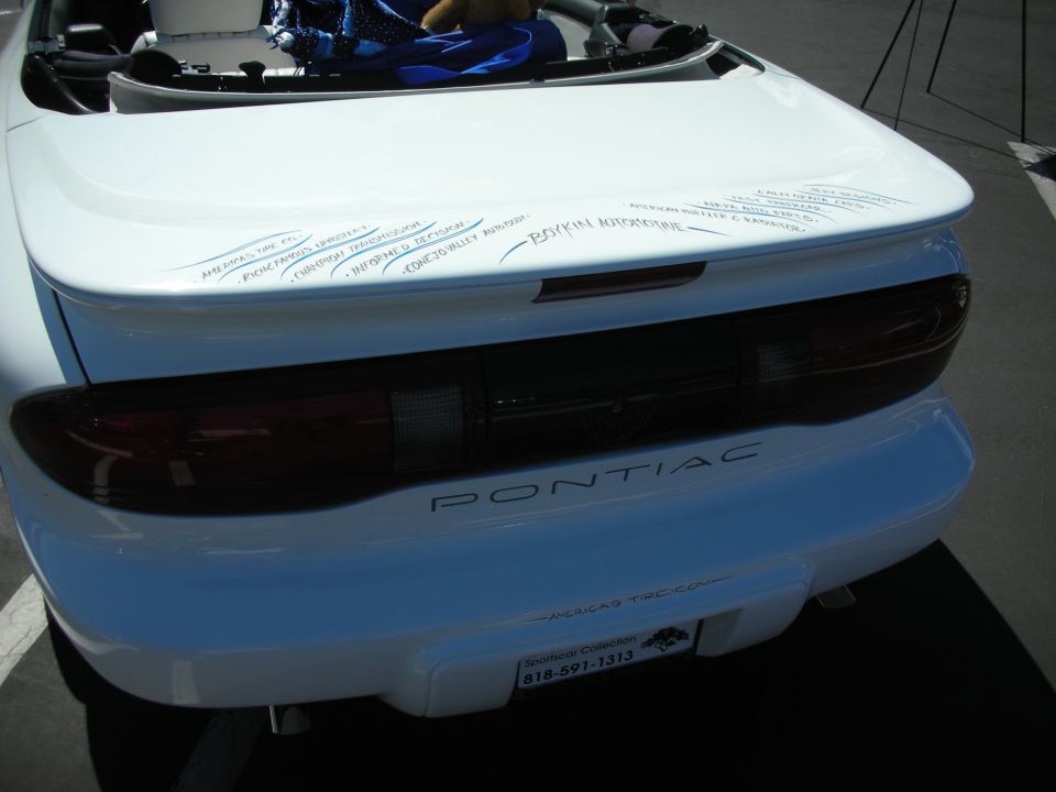 White Pontiac Firebird rear with 'PONTIAC' badge and a license plate frame from 'Americas TCC'