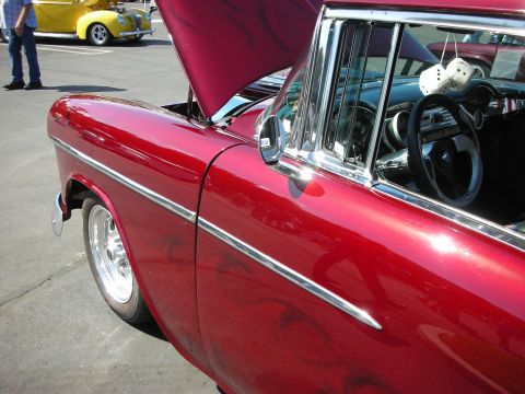 1998 Ford Crown Victoria - Interior view of a red classic car with fuzzy dice, parked at a car show with another vehicle nearby.