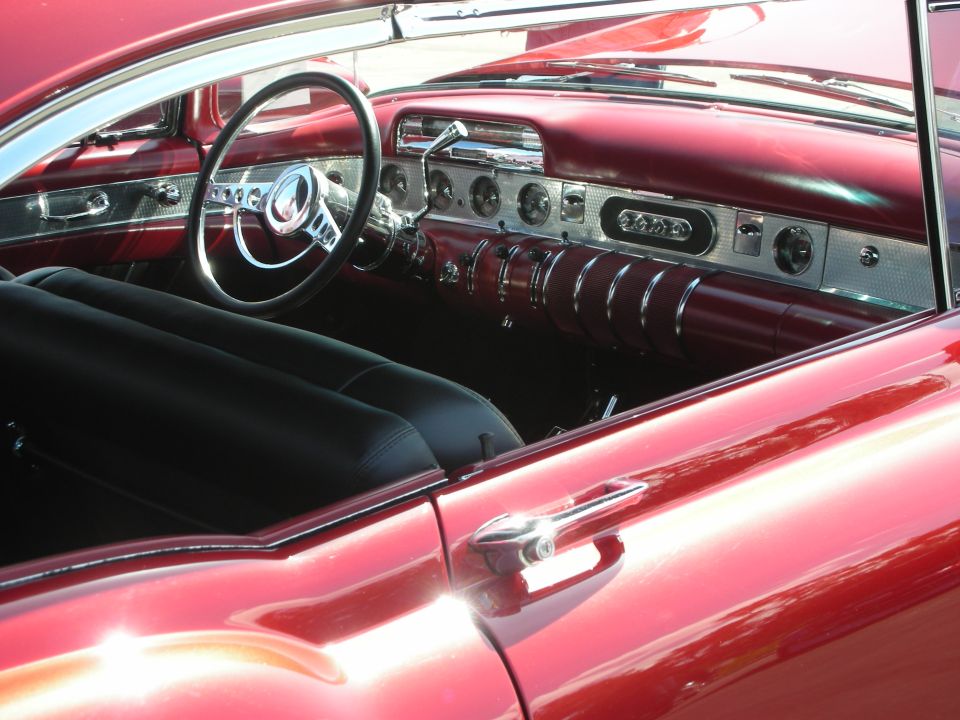 Red car interior with black seats and chrome accents on the dashboard and steering wheel