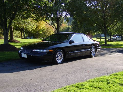 1996 Mercury Grand Marquis - A black Lincoln Mark VIII coupe is parked on an asphalt driveway with trees and grass in the background.