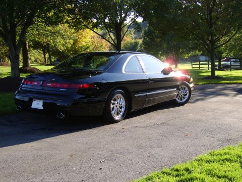 1996 Mercury Grand Marquis - A black coupe with a distinctive body style is viewed from a three-quarter front angle.