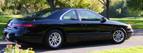 1996 Mercury Grand Marquis - A black coupe is parked on a paved driveway, with trees and grass visible in the background.