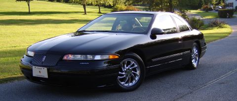 1996 Mercury Grand Marquis - This black Lincoln Mark VIII coupe is parked on a road with trees and a lawn visible.