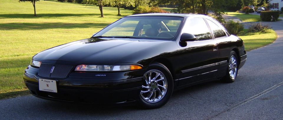 Black Lincoln coupe, front 3/4 view, chrome wheels, parked on driveway