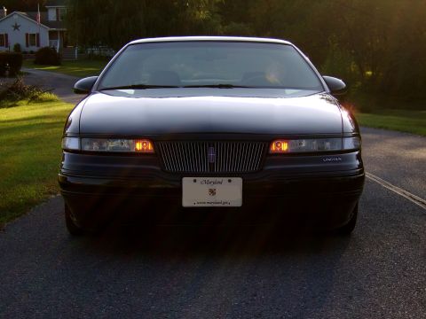 1996 Mercury Grand Marquis - Black Lincoln sedan parked on a road during sunset. The grille and headlights are visible.