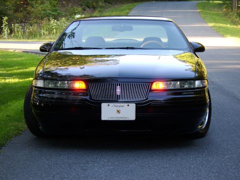 1996 Mercury Grand Marquis - A black Lincoln Town Car is parked on a paved road with grass on the sides.