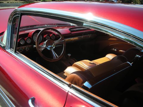 1998 Ford Crown Victoria - The custom interior of a classic red car features tan leather seats and a polished steering wheel.