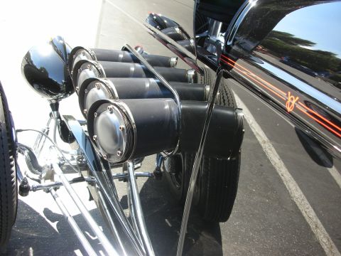 1998 Ford Crown Victoria - The side of a custom hot rod is shown, focusing on its unique exhaust system and decorative pinstriping.