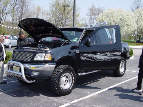 2001 Ford Mustang - A black Ford F-150 pickup truck is displayed with its hood and driver door open.