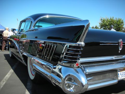 1998 Ford Crown Victoria - A classic black car with extensive chrome detailing is parked outdoors under a clear blue sky.