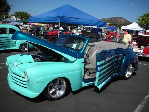 1998 Ford Crown Victoria - A customized convertible is displayed with its hood and door open at an outdoor car show.