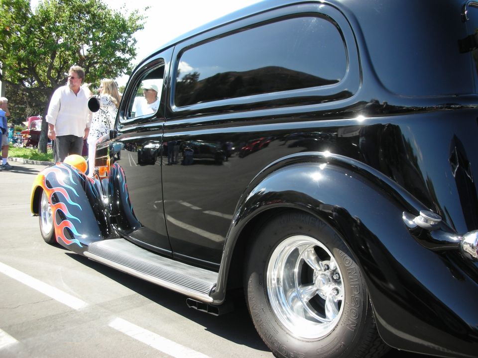 Black sedan with flame decals on rear fender, seen from the rear quarter