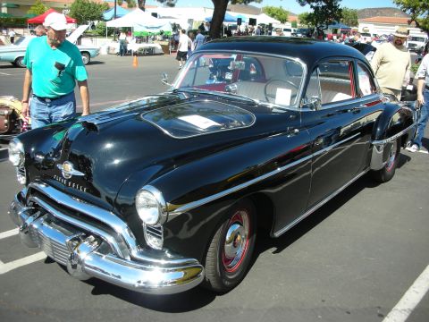 1998 Ford Crown Victoria - A classic black Oldsmobile 88 is displayed at an outdoor car show event.