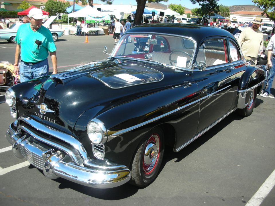 Black 1950 Oldsmobile 88 coupe parked outside with people around
