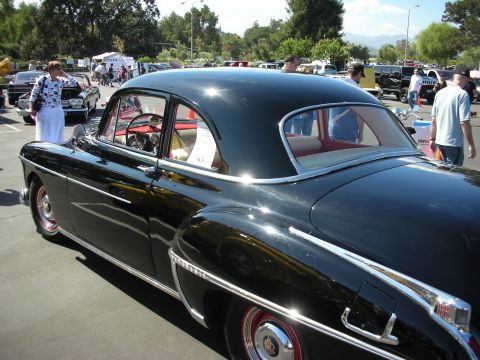 1998 Ford Crown Victoria - This classic black sedan has a distinctive body style, likely from the early 1950s, at a car show.