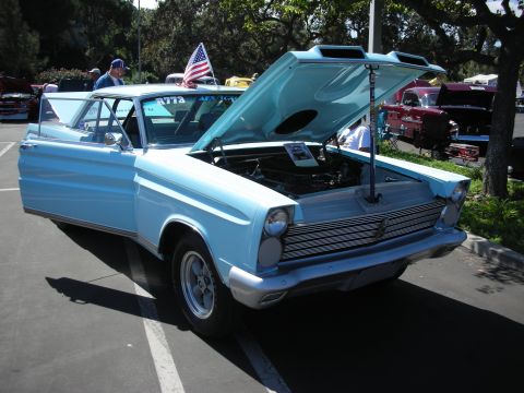 1998 Ford Crown Victoria - A light blue 1965 Mercury Comet station wagon is displayed with its hood and driver's door open at a car show.