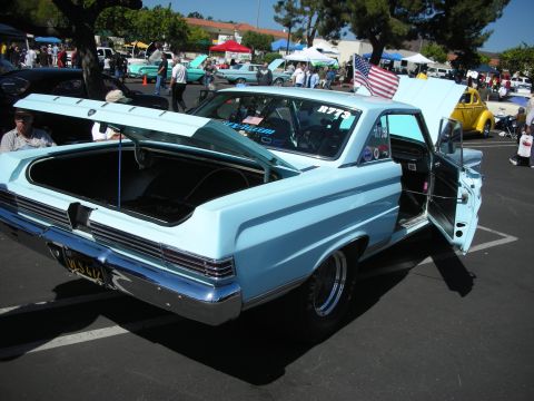 1998 Ford Crown Victoria - A light blue coupe is displayed at a car show with its trunk and door open, an American flag on the roof.