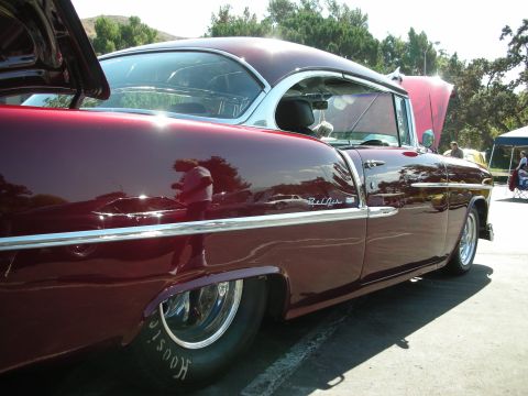 1998 Ford Crown Victoria - A classic maroon 1955 Chevrolet Bel Air is displayed at a car show, its hood open to reveal the engine bay.