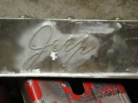 1948 Jeep Wrangler - A close-up view of a Jeep emblem, possibly from a vehicle part, with visible metalwork and some wear.