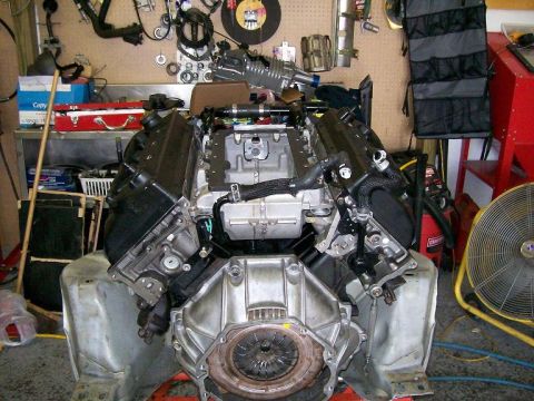 2007 Ford Mustang - Engine assembly in a workshop setting with tools and equipment in the background.