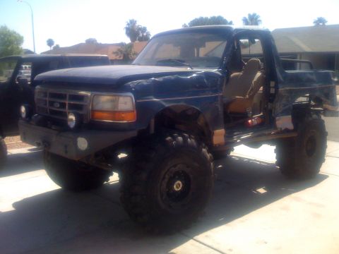 1994 Ford Bronco - This modified 1994 Ford Bronco features oversized tires, a custom front bumper, and a removed driver's door, suggesting extensive off-road…