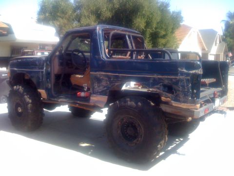 1994 Ford Bronco - This heavily modified SUV, likely from the 1980s, has been stripped down and equipped for off-road use.