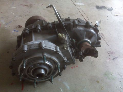 1994 Jeep Cherokee - A silver and black transfer case is shown from a side angle on a concrete surface.