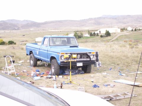 1977 Ford F-250 - A blue 1977 Ford F-250 pickup truck is parked in a field with tools and equipment scattered around it.