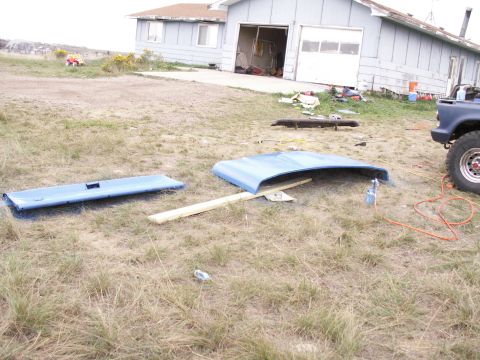 1977 Ford F-250 - Car hood and tailgate are on the ground next to a house and a blue truck.