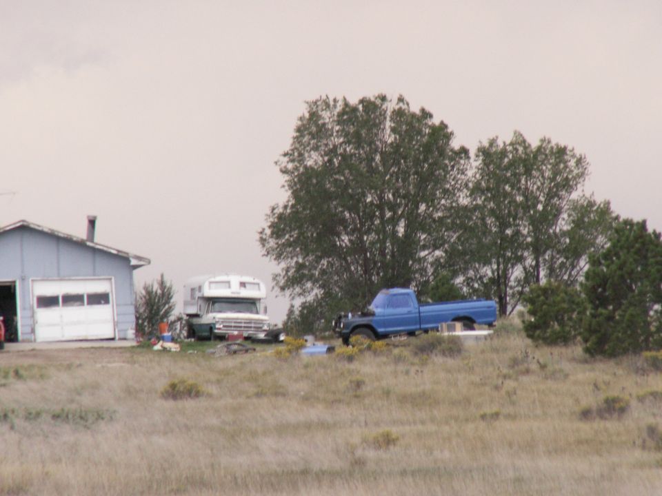 Blue pickup truck and RV parked near a garage