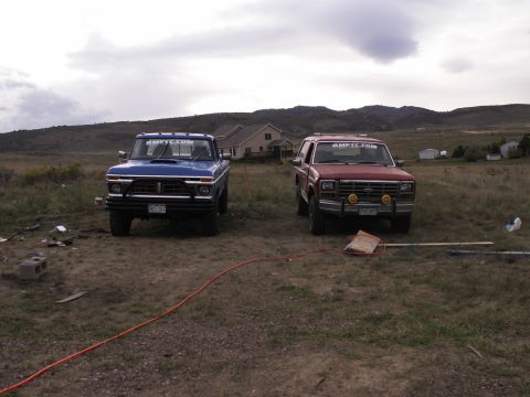 1977 Ford F-250 - Two trucks, a blue Ford F-250 and a red SUV, are parked outdoors under a cloudy sky.