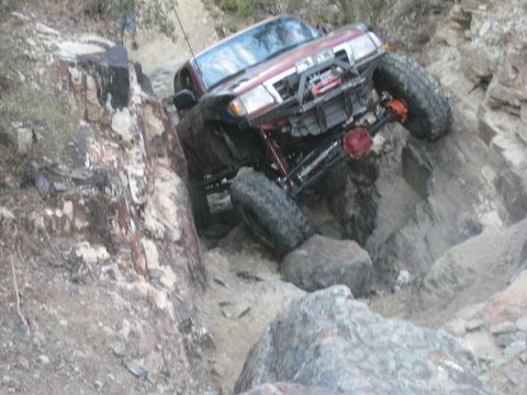1985 Toyota 4Runner - This modified SUV is tackling a challenging off-road course, demonstrating its capability on rough terrain.