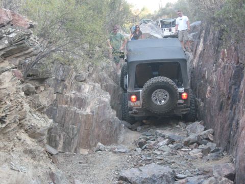 1985 Toyota 4Runner - Several Jeeps are seen on a challenging off-road trail with steep rock formations.