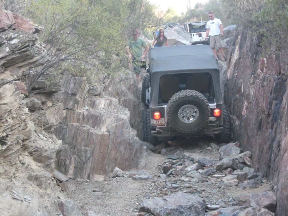 Jeep Wrangler navigating a rocky trail with people watching