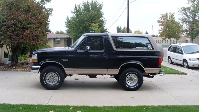 Black and tan Ford Bronco Eddie Bauer, side profile on a driveway