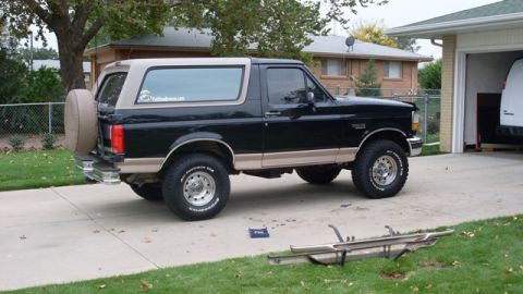 1996 Ford Bronco - This two-tone Ford Bronco is parked in a suburban driveway next to a garage.