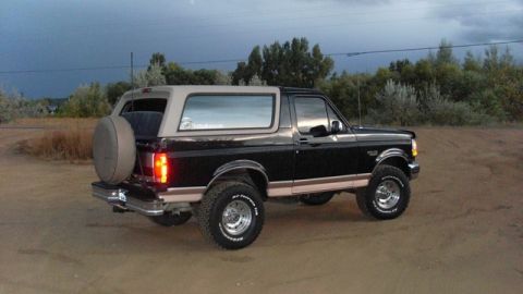 1996 Ford Bronco - This 1996 Ford Bronco is shown from the rear-three-quarter view on a dirt road with a cloudy sky.