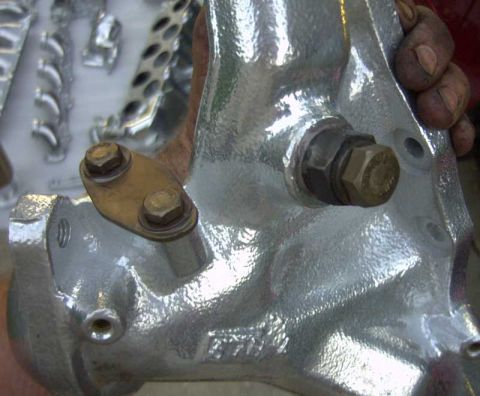 1997 Ford Taurus - Close-up of a silver-colored exhaust component, a brass bracket secured by two hex bolts.