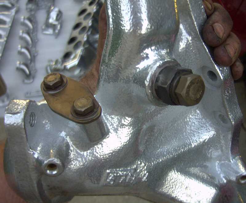 Silver exhaust part with brass bracket and hex bolts
