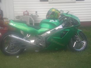 1995 Ford Probe - A green Kawasaki Ninja motorcycle is parked outside next to a house with a helmet on its seat.