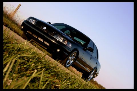 2003 Mercury Marauder - A black 2003 Mercury Marauder is angled on a grassy roadside under a clear sky.