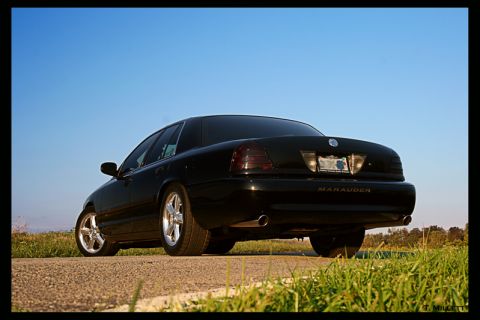 2003 Mercury Marauder - Rear view of a black 2003 Mercury Marauder parked on a dirt road with a clear blue sky.