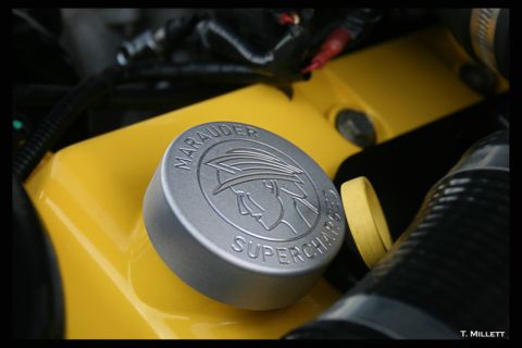 2003 Mercury Marauder - Close-up of a 'Marauder Supercharged' emblem on a yellow engine component.