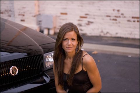 2003 Mercury Marauder - A woman poses beside the front end of a black Mercury Marauder, showing its distinctive grille and emblem.