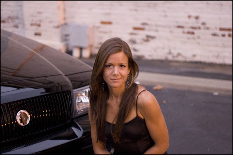Woman in black dress next to a 2003 Mercury Marauder's grille and headlight