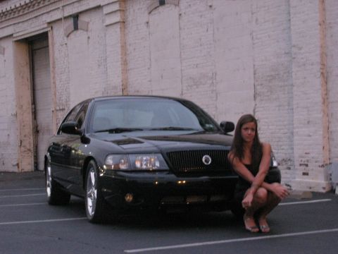 2003 Mercury Marauder - A black 2003 Mercury Marauder is parked in front of a brick building with a woman posing beside it.