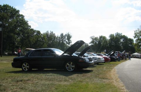 2003 Mercury Marauder - Several cars, including a 2003 Mercury Marauder, are parked with their hoods open at an outdoor event.