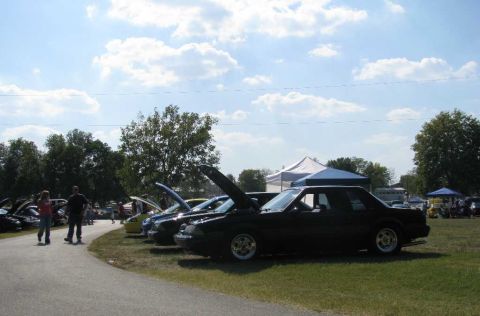 2003 Mercury Marauder - Several cars are parked with hoods open at an outdoor event under a partly cloudy sky.