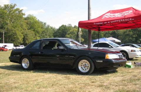 2003 Mercury Marauder - A black coupe with aftermarket wheels is parked on a grassy field under a red tent.