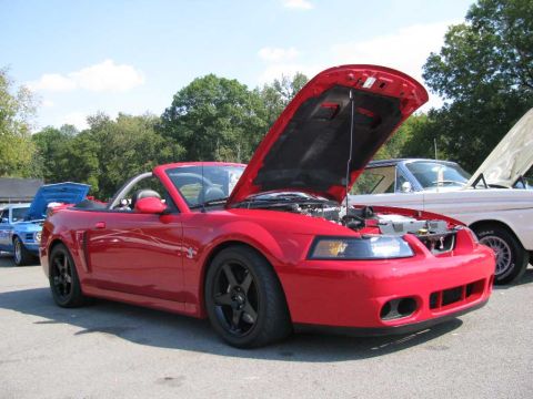 2003 Mercury Marauder - A red convertible Mustang is parked with its hood open, alongside other vehicles.